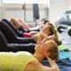 Frauen liegen auf Matten in einem Fitnesskurs und führen gemeinsam Übungen durch, um ihre Halswirbelsäule zu stärken.