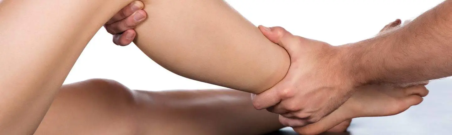 Ein Therapeut hält und bewegt das Bein eines Patienten, um die Mobilität und Flexibilität des Gelenks in einer physiotherapeutischen Behandlung zu verbessern.