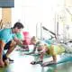 Eine Gruppe von Männern und Frauen die durch Anleitung eines Trainers gemeinsam eine Plank-Übung in einem Fitnesskurs ausführt, um ihre Kraft und Stabilität des Rückens zu trainieren.