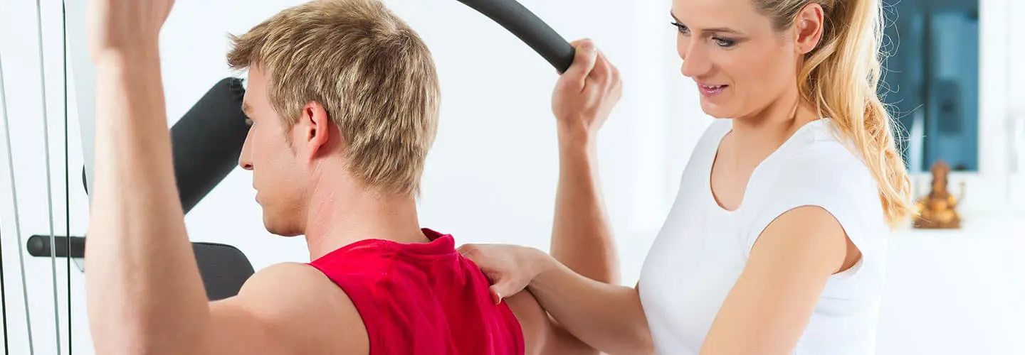 Ein Physiotherapeut unterstützt einen Patienten beim Training an einem Kraftgerät im Therapiezentrum Marzipanfabrik, um Muskulatur und Beweglichkeit zu fördern.